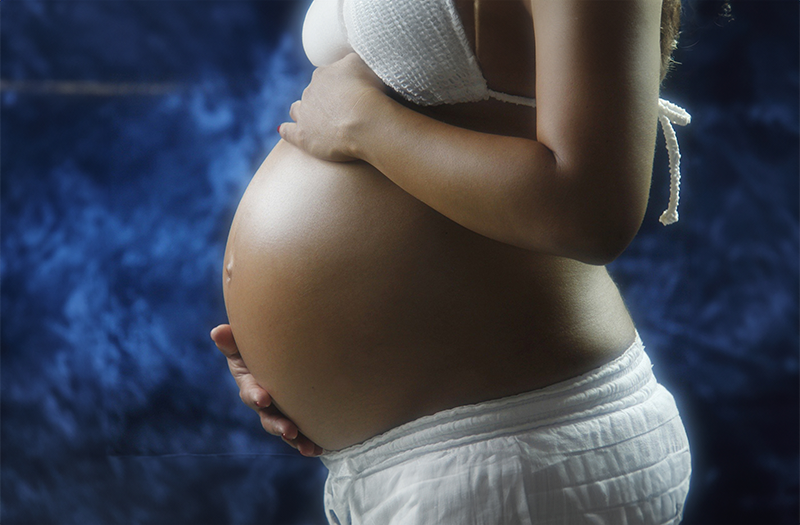 Mulher gravida com as mãos na barriga